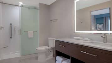 A modern bathroom with a glass-enclosed shower, a toilet, and a vanity with a mirror.