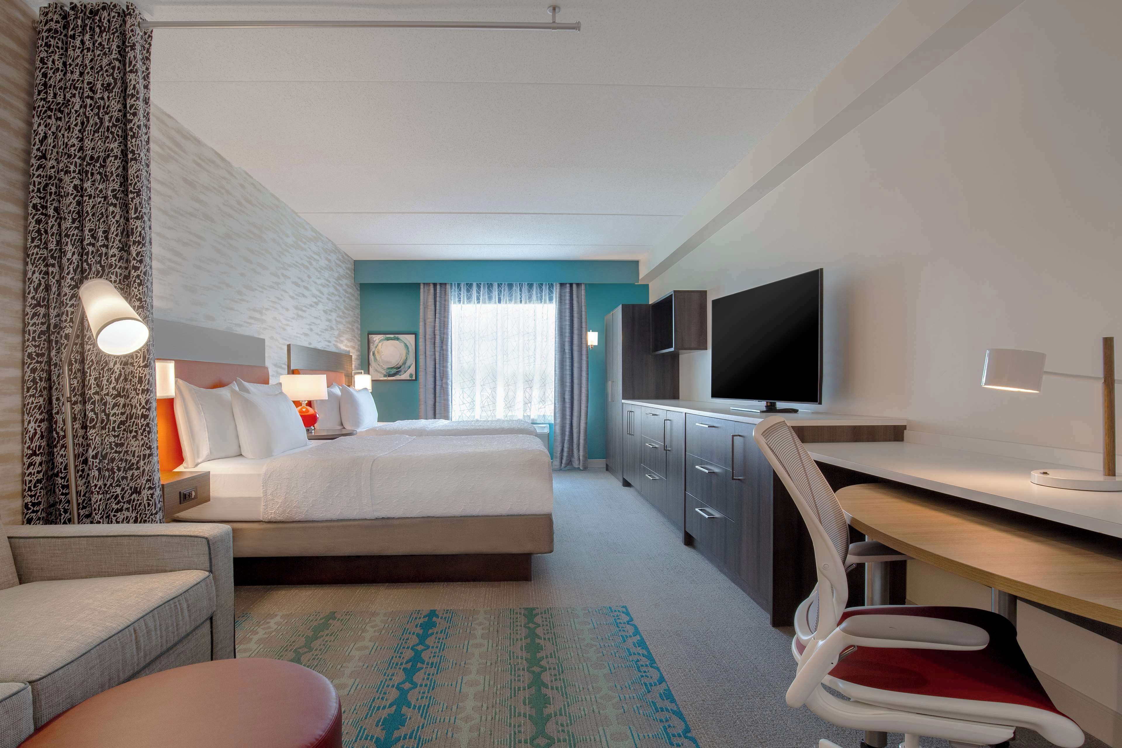 Une chambre d’hôtel avec un lit, un bureau, une télévision et une chaise.