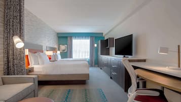 Une chambre d’hôtel avec un lit, un bureau, une télévision et une chaise.