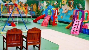 Ein Kinderspielbereich mit Rutsche, Klettergerüsten und Schaukeln.