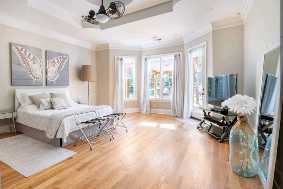 A bedroom with a bed, a TV, and a window.