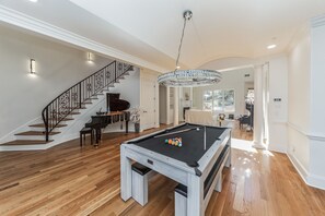 A spacious living area with a pool table, a grand piano, and a staircase. - Tennessee Modern Manor (Eads)