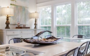 A dining area with a table set for two, a decorative metal bowl on the table, and two lamps on a sideboard.