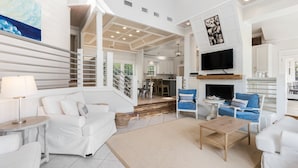 A spacious living area with a white sofa, blue armchairs, a coffee table, and a fireplace. - Vast Luxurious Home in Gated Community + Pool (Seacrest)