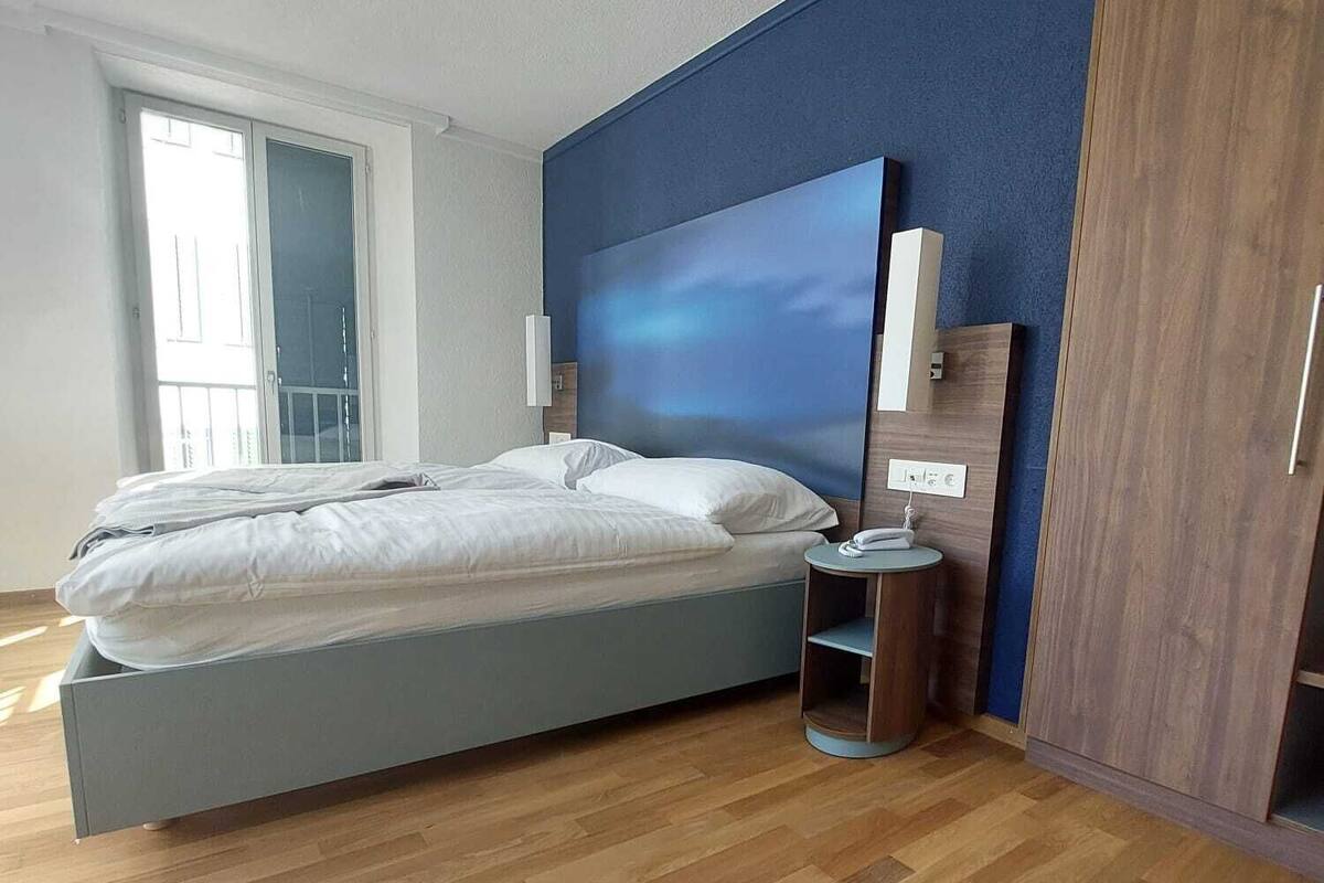 A modern bedroom with a bed, a nightstand, and a wardrobe.