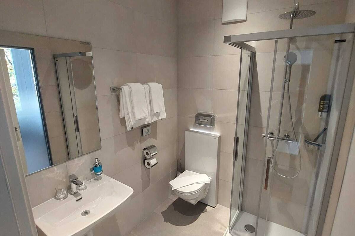 A modern bathroom with a glass-enclosed shower, a white sink, and a toilet.