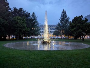Una fuente en un parque con un edificio al fondo.