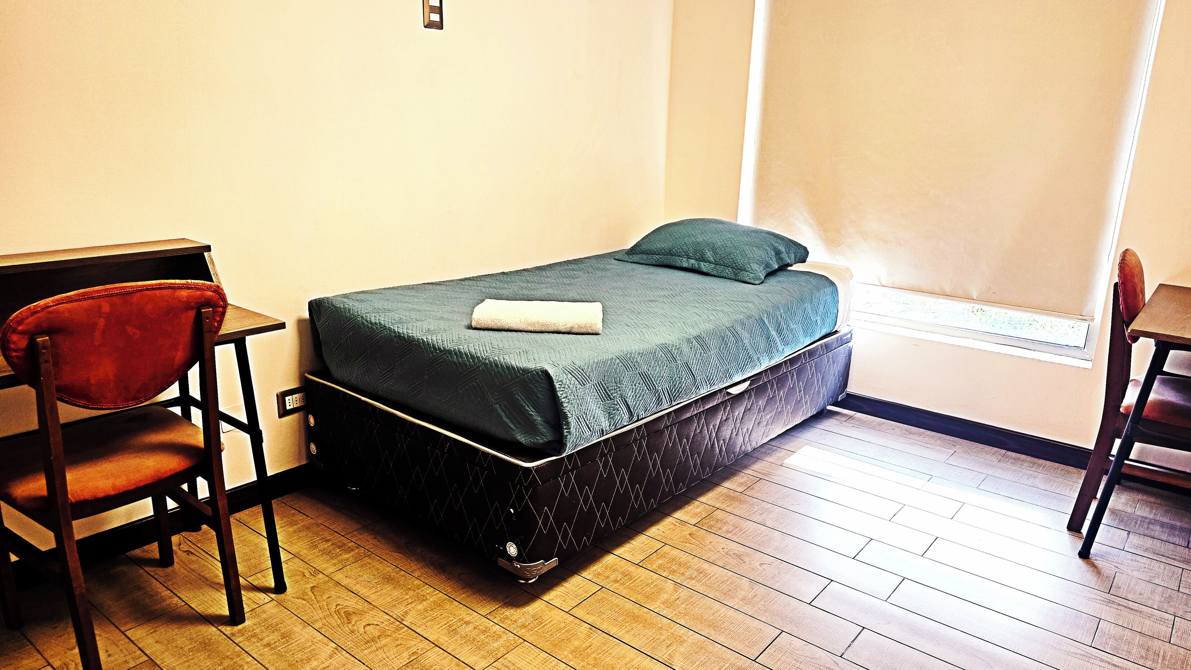 A compact room with a bed, a desk, and a chair.