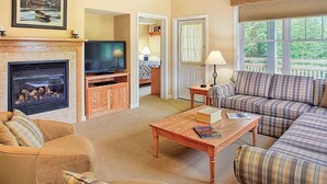 Ein gemütliches Wohnzimmer mit Kamin, Fernseher, Sofa und Couchtisch.