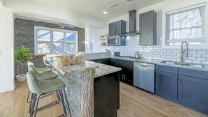 A modern kitchen with a central island, dark cabinetry, and a stone accent wall.