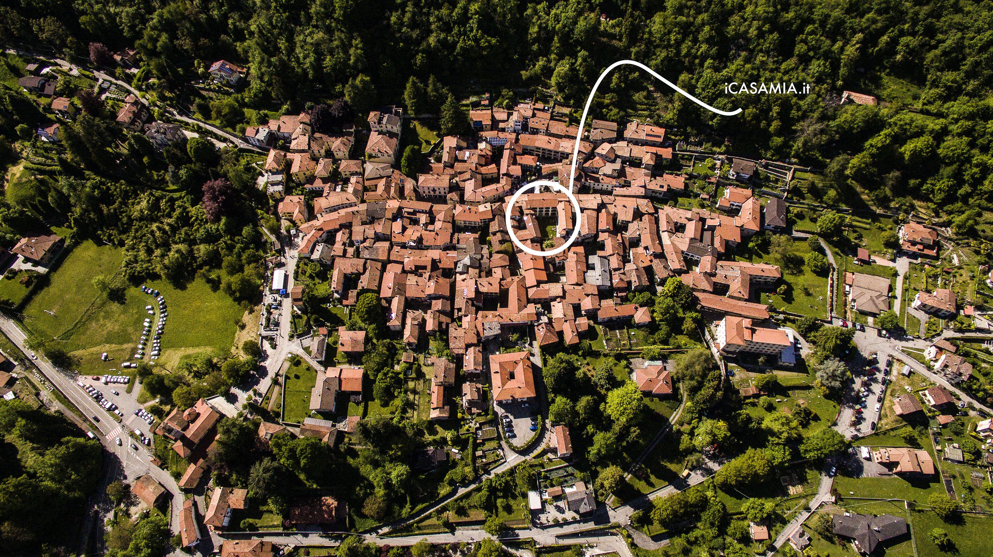 Vista aérea de un pueblo densamente poblado con calles estrechas y casas muy juntas, rodeado de vegetación.