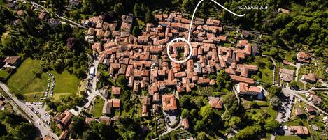 Vista aérea de un pueblo densamente poblado con calles estrechas y casas muy juntas, rodeado de vegetación.