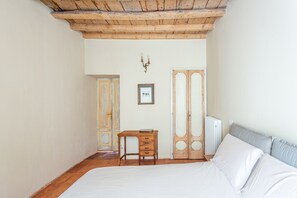 Una camera da letto con un letto di legno, una piccola scrivania di legno, un termosifone e un'armadio di legno.