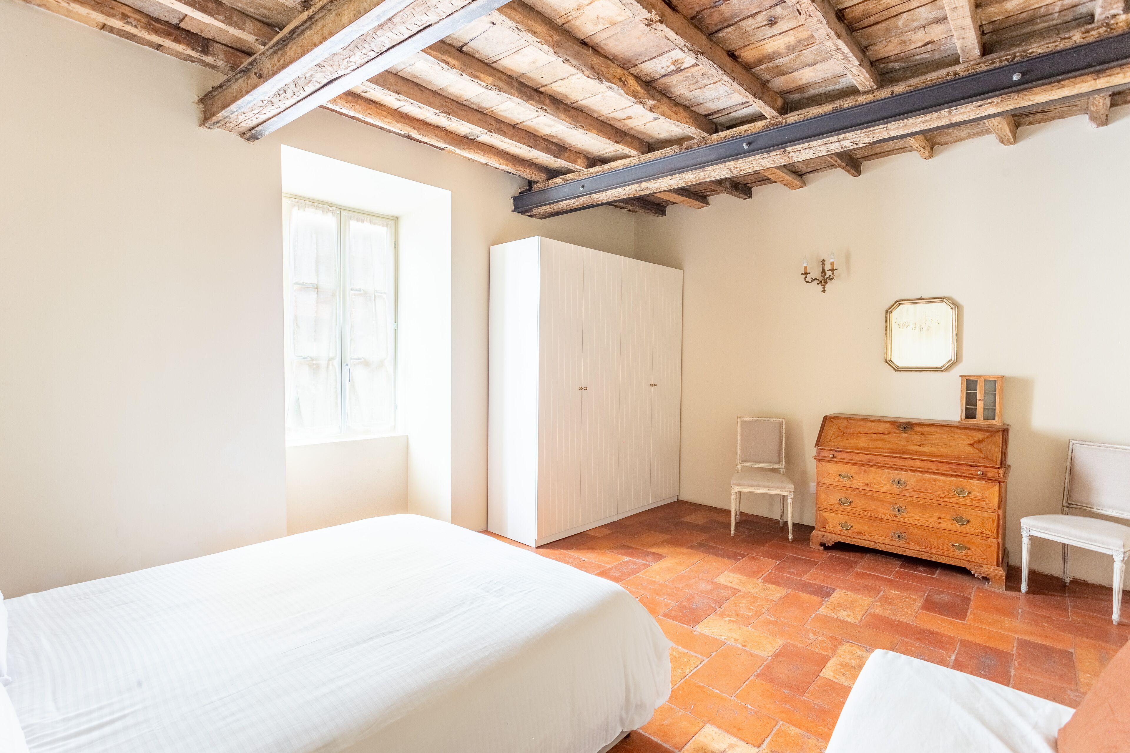 Ein Schlafzimmer mit einem Bett, einem Kleiderschrank, einem Schminktisch und einem Sessel.