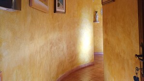 Ein gebogener Korridor mit gelben Wänden und Fliesenboden.