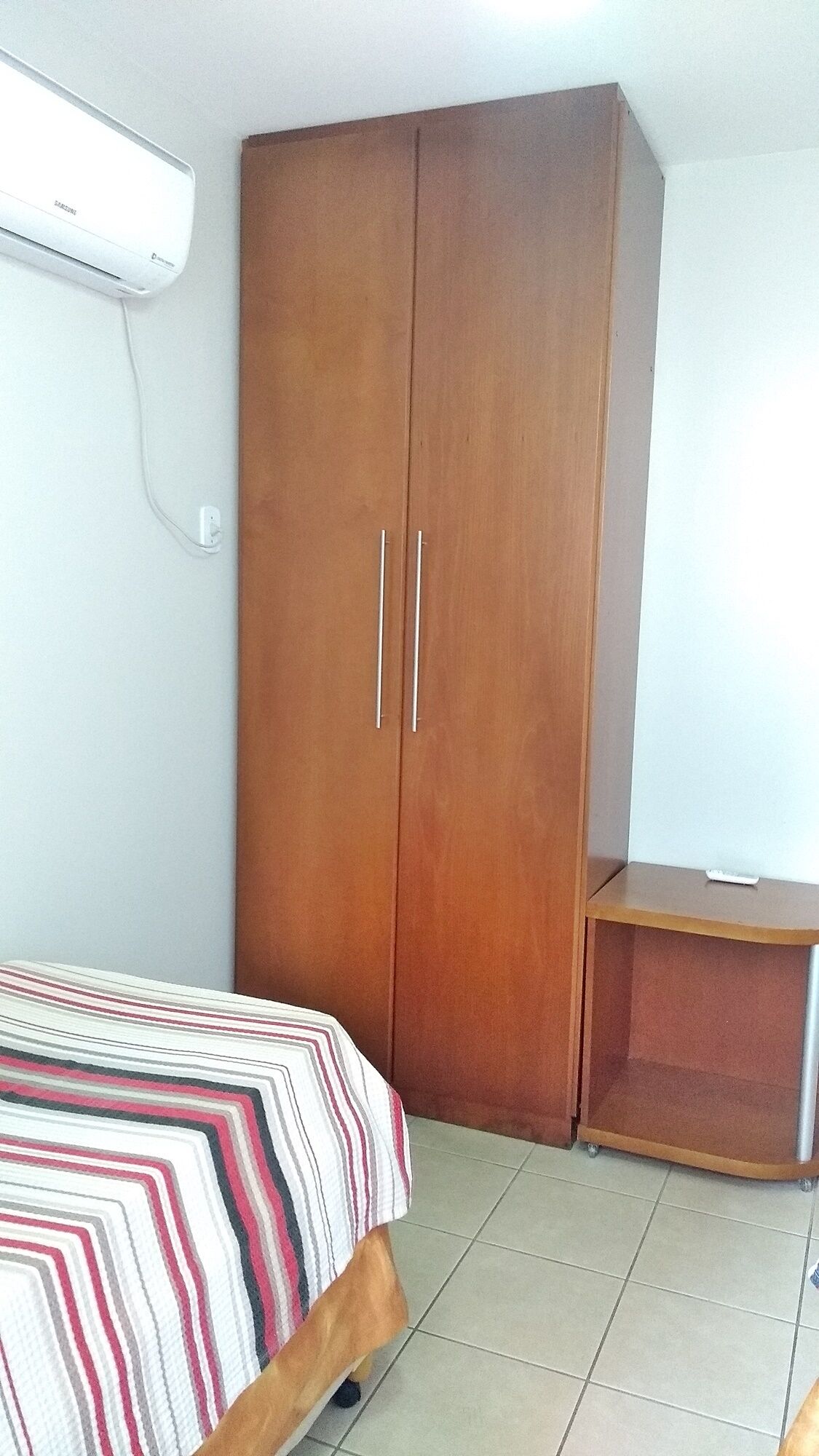 A bedroom with a bed, a wardrobe, and a small desk.