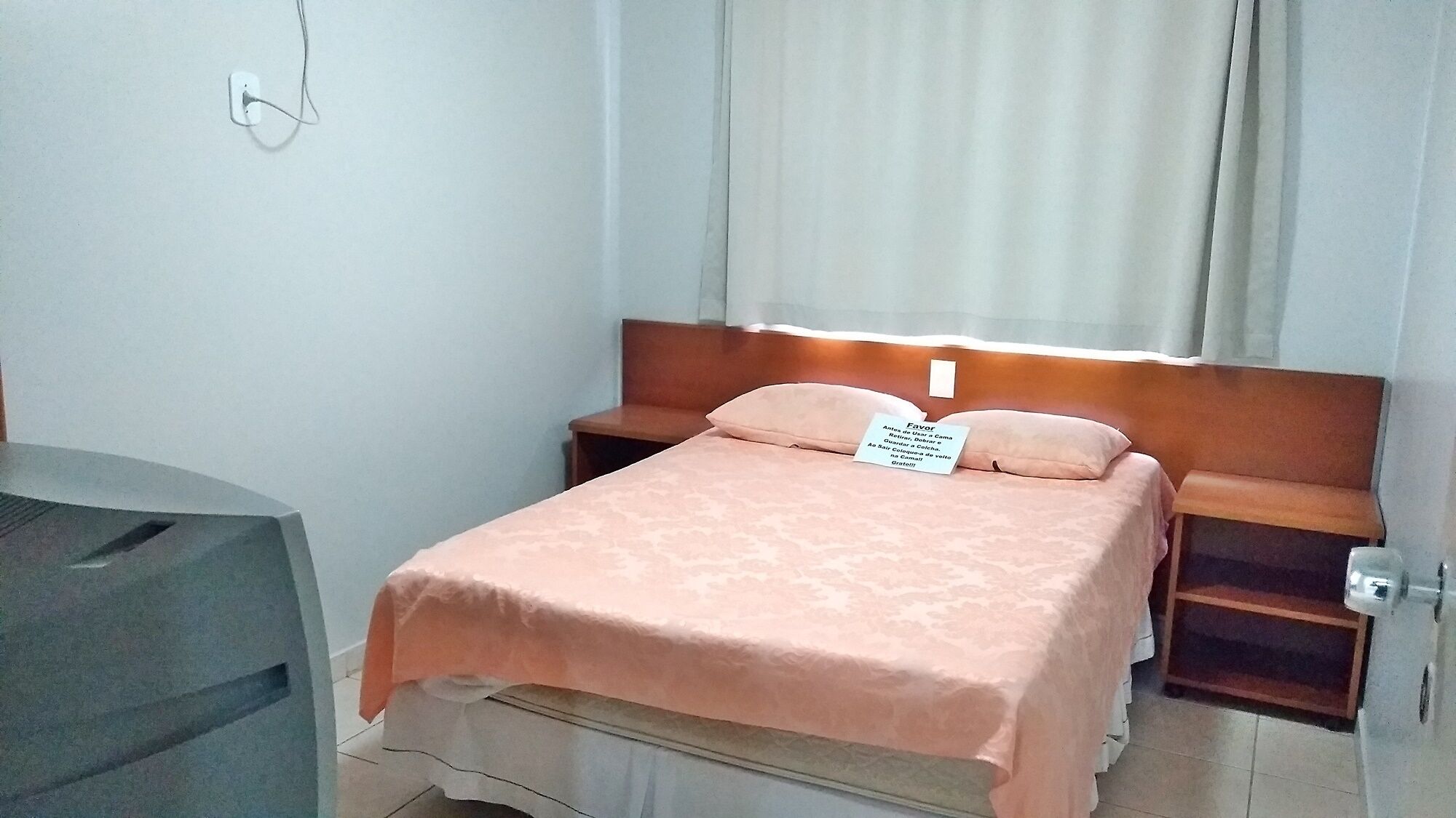 A hotel room with a bed, a nightstand, a desk, and a chair.