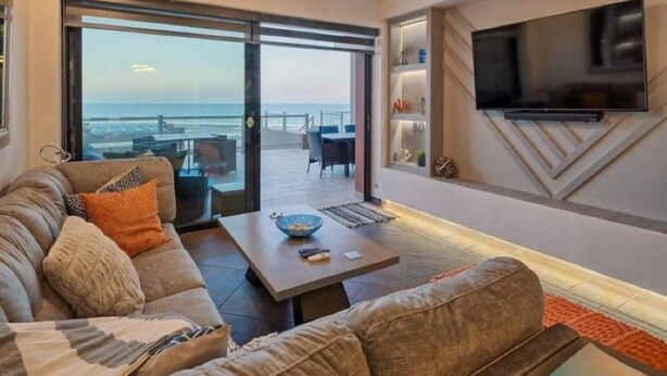 A modern living room with a sofa, coffee table, and a flat-screen TV mounted on the wall. - Gorgeous Ocean Front Resort J 107 (Puerto Peñasco)