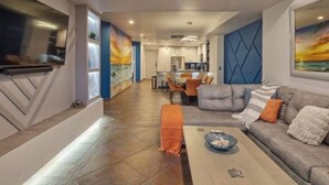 A modern living room with a grey sofa, a coffee table, and a TV mounted on the wall. - Gorgeous Ocean Front Resort J 107 (Puerto Peñasco)