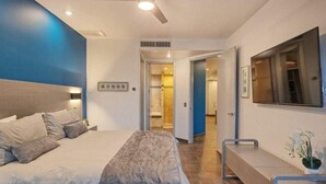 A modern bedroom with a large bed, a ceiling fan, and a view into the bathroom. - Gorgeous Ocean Front Resort J 107 (Puerto Peñasco)