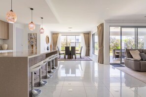 Una cocina moderna con una isla central, taburetes de bar e iluminación colgante.