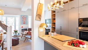 A modern kitchen with wooden countertops, a built-in oven, and a hanging light fixture.