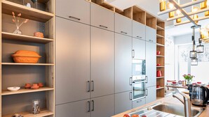A modern kitchen with grey cabinets, a wooden countertop, and a fruit bowl.