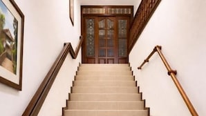A staircase with wooden handrails and beige steps leading to a door with glass panels. - Hospedaje Camino Real  (Salento)