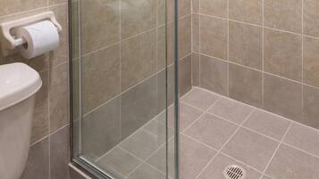 A bathroom with a glass shower enclosure, a toilet, and a towel rack.