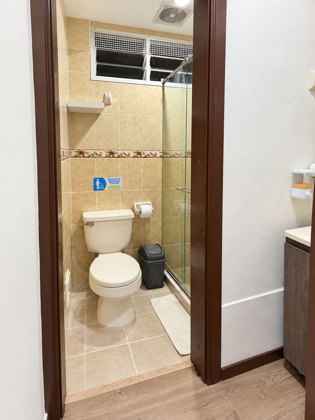 Un baño con inodoro, un cubo de basura y zona de ducha.