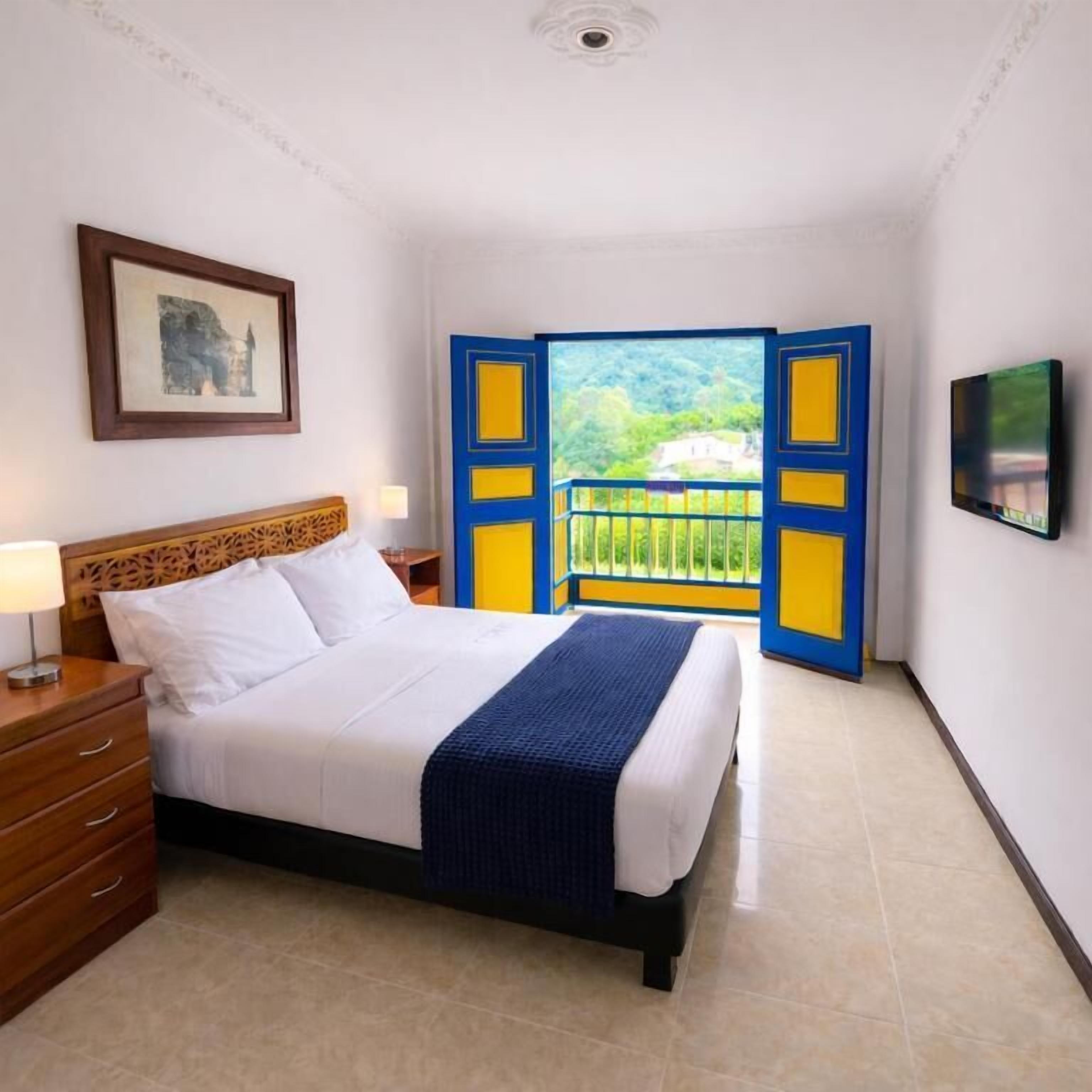 Une chambre d’hôtel avec un lit, une table de chevet, une télévision et un balcon avec vue.