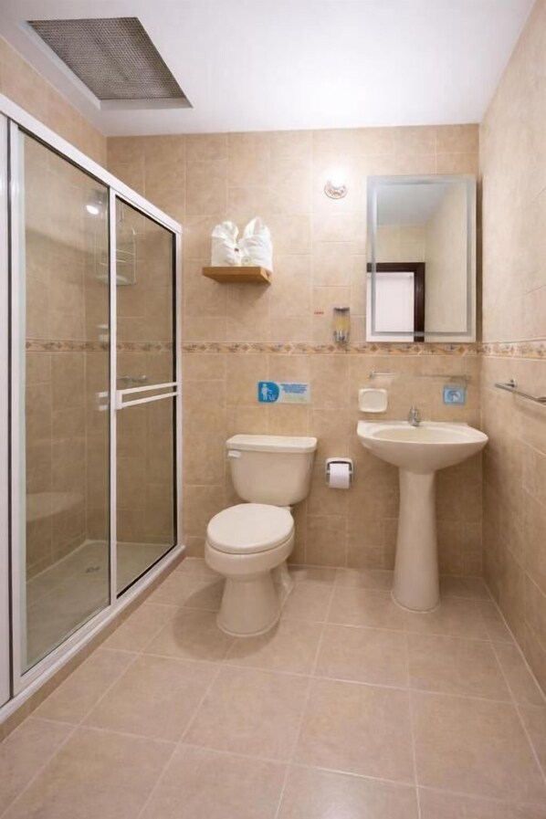 A bathroom with a glass shower enclosure, a toilet, and a pedestal sink.