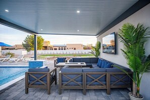 An outdoor patio with a pool, seating area, and a view of buildings in the background.