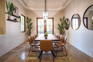 A conference room with a long table, multiple chairs, a chandelier, and decorative mirrors.