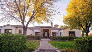 A two-story house with a stone archway entrance, a brick pathway leading to the front door, and well-maintained hedges. - Epic Resort: Pool, Hot Tub, Pickleball & More! (Chandler)