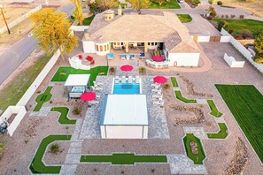 An aerial view of a property with a swimming pool, outdoor seating, and landscaped garden areas.