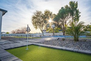 A well-maintained outdoor area with a putting green, a checkered flag, and a basketball hoop.