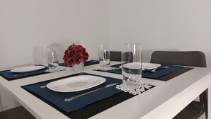 A dining table set with plates, cutlery, glasses, and a vase of red flowers. - Apartment Adora Split (Split)