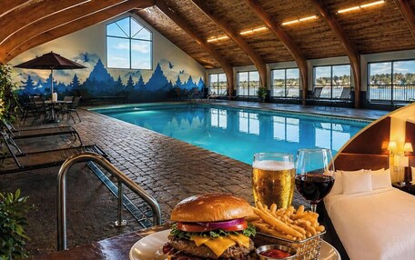 A poolside dining area with a view of the pool, a burger, fries, and drinks.