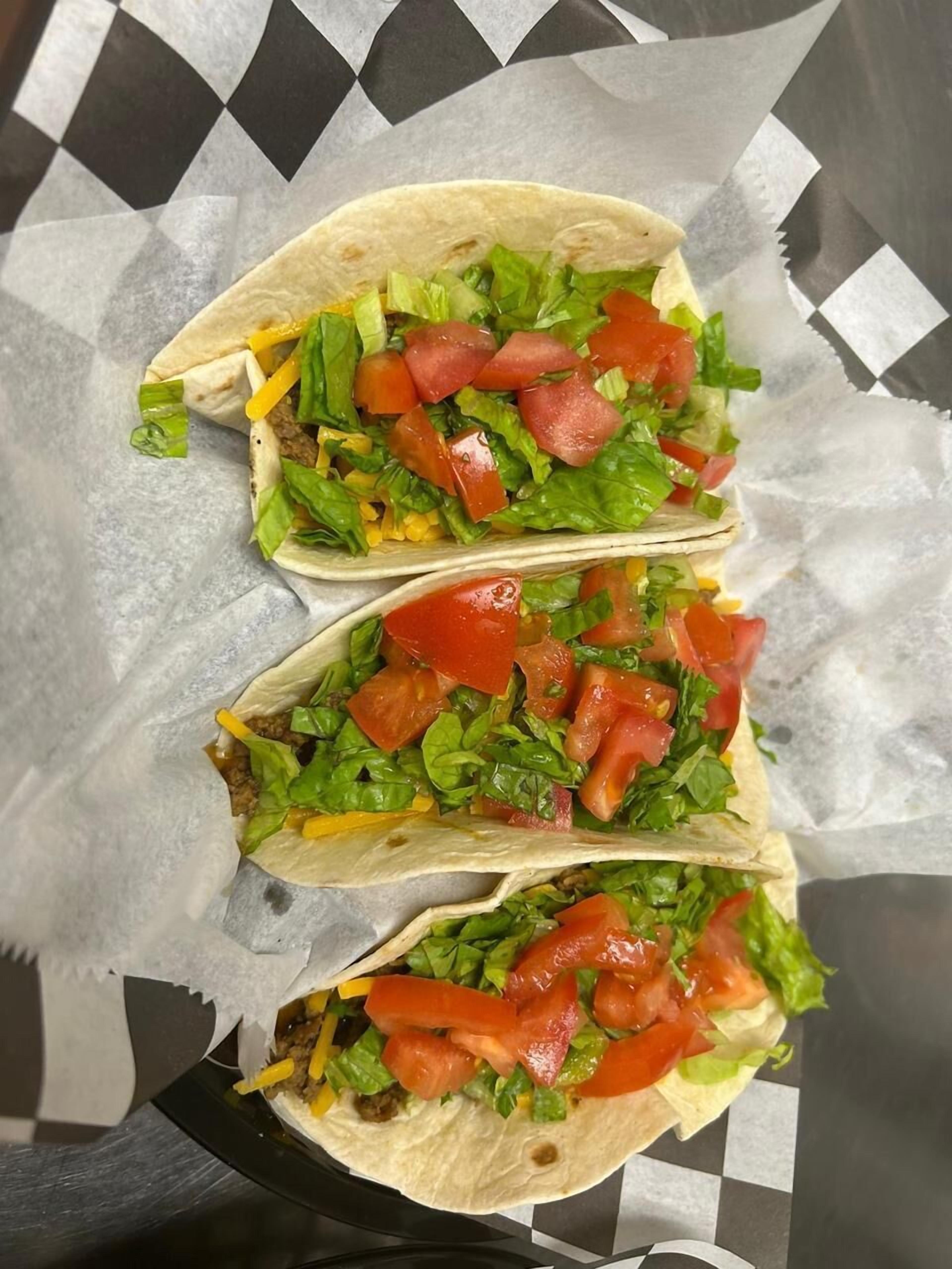 Three tacos on a checkered surface.