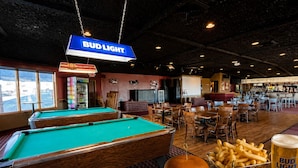 A billiards table, pool tables, and a bar area with a Bud Light sign.