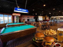 Mesa de billar, mesas de pool y zona de bar con un cartel de Bud Light.
