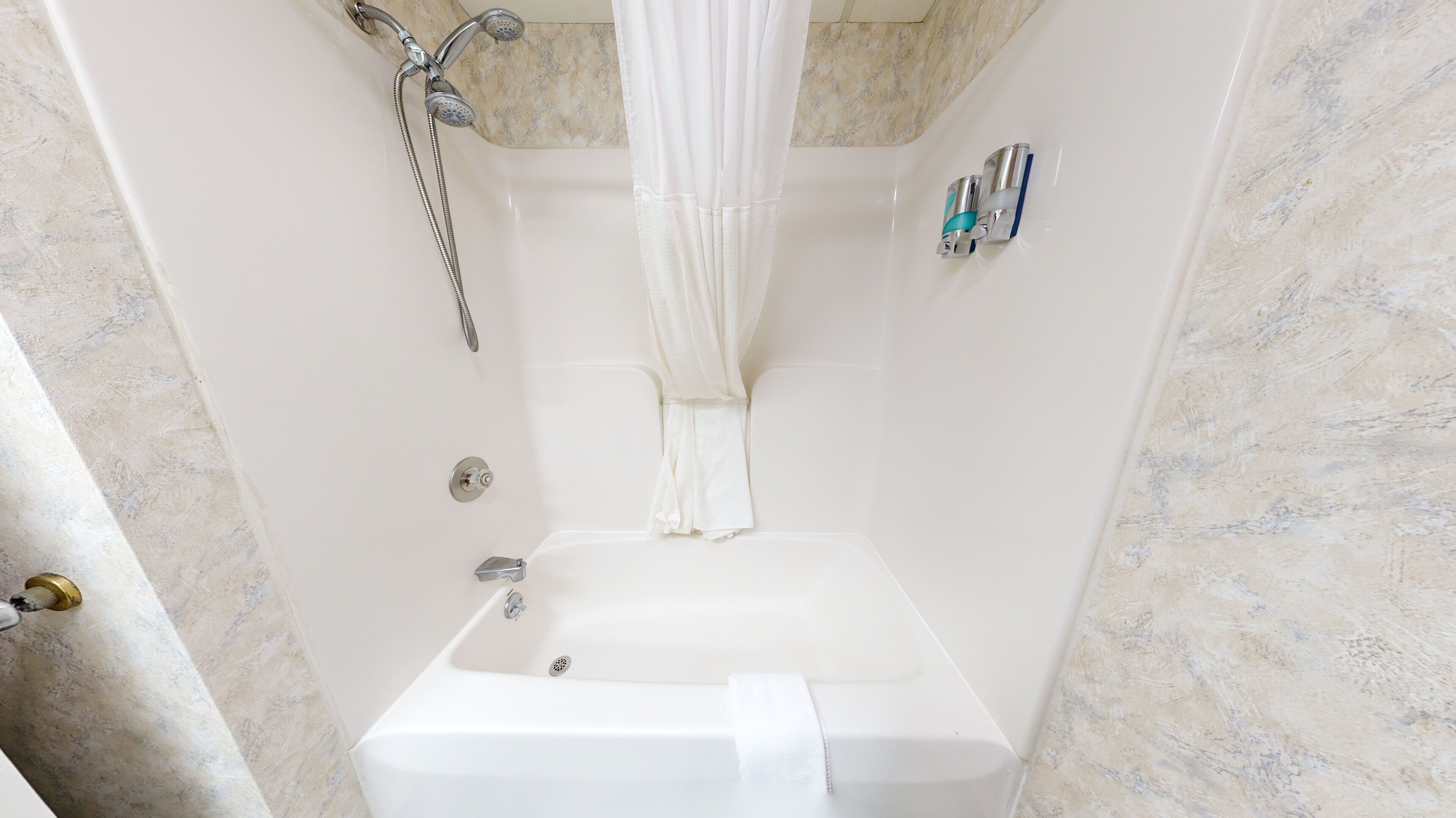 A bathroom with a bathtub, a shower head, and a curtain.