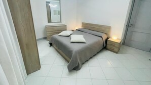 A bedroom with a bed, bedside tables, a mirror, and a door.