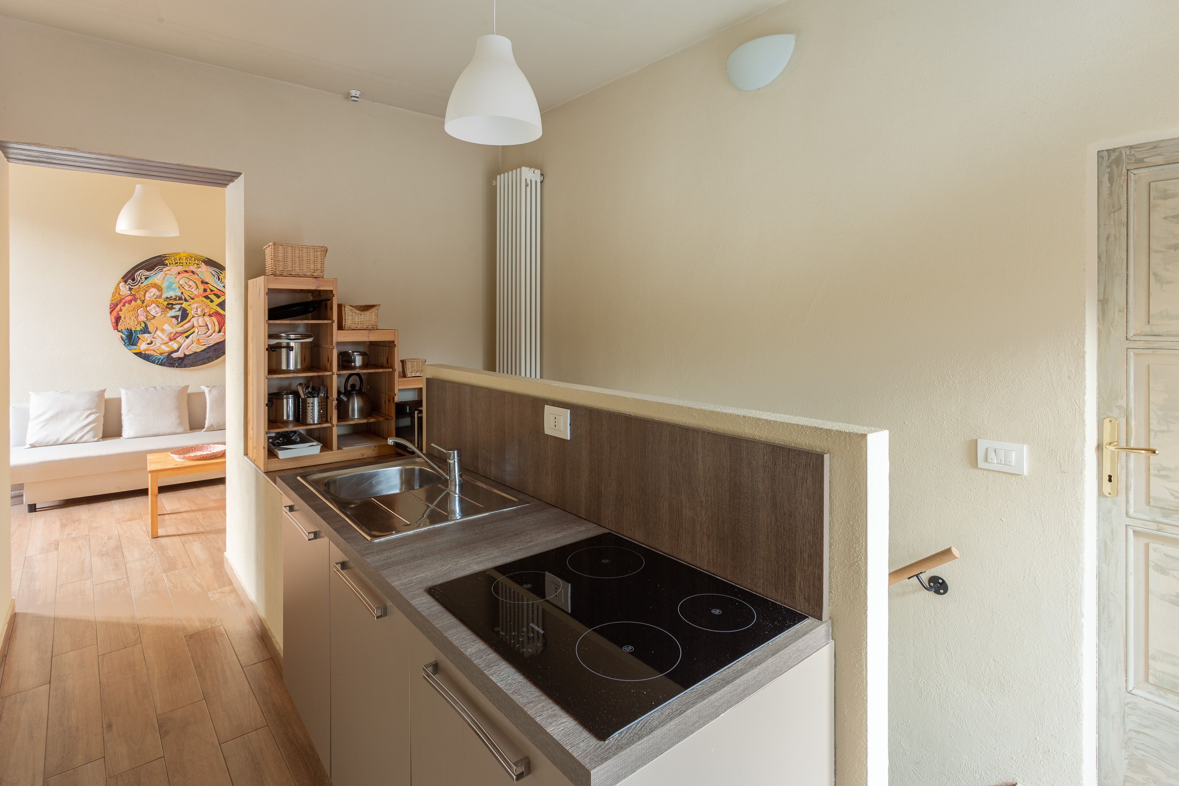 Een praktische keuken met een fornuis, houten planken en een zithoek met een bank en tafel.