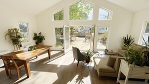 Quarto espaçoso com teto alto, janelas amplas e porta de vidro deslizante para um pátio externo.