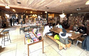 Une librairie avec des étagères, des tables et des chaises en bois, où les clients peuvent s’asseoir et parcourir les ouvrages.