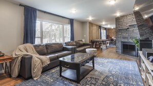 Ein modernes Wohnzimmer mit Ledersofa, Glastisch und Kamin aus Stein.