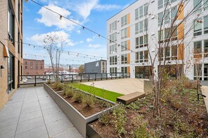 Un jardin sur le toit, avec une pelouse verdoyante, des jardinières et une vue sur le paysage urbain.