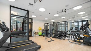 Una sala de gimnàstica moderna amb cintes de córrer, peses i pilotes d'exercici.